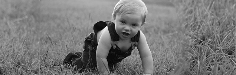 A photograph of a baby crawling in a field.