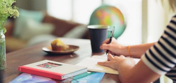 A photograph of a person writing at a desk. 