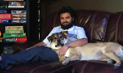 A photograph of Michael Kuehn on a couch with a dog.