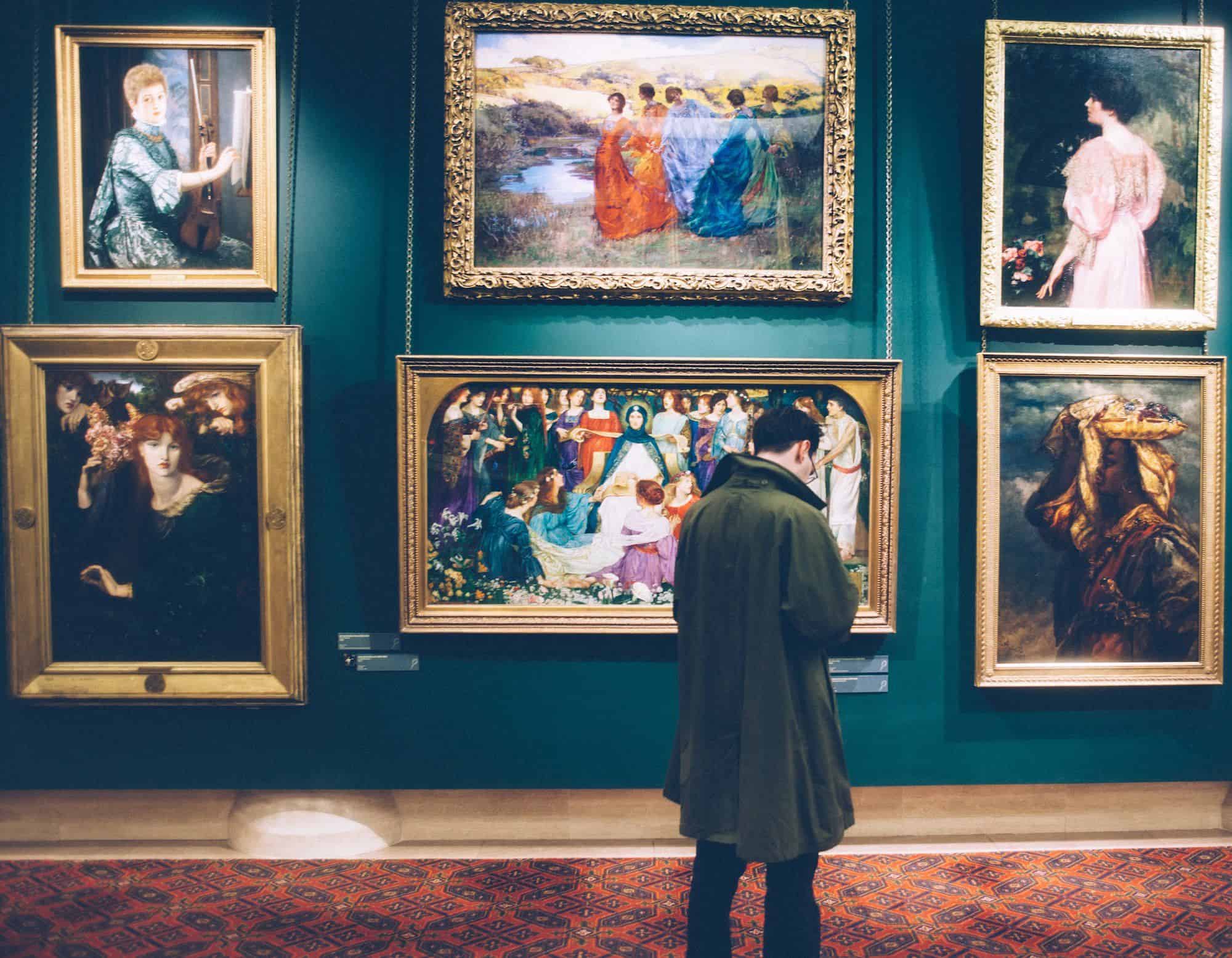 A photograph of a man standing in front of a museum gallery wall.