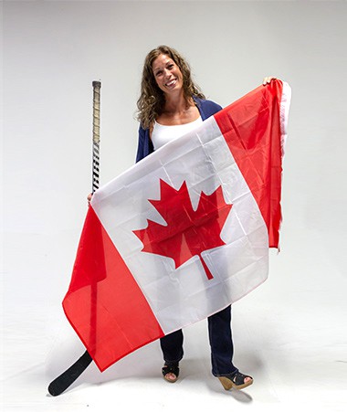 Christina Griggs holding a Canadian flag and a hockey stick.