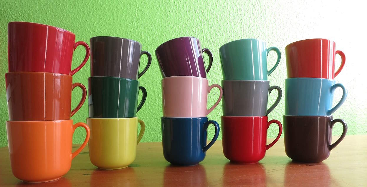 A photograph of five stacks of different colored mugs. 