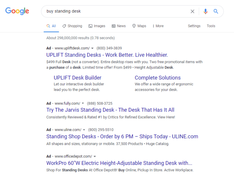 A screenshot of a Google search result for buy standing desk. Each ad is text only and includes a short description. 