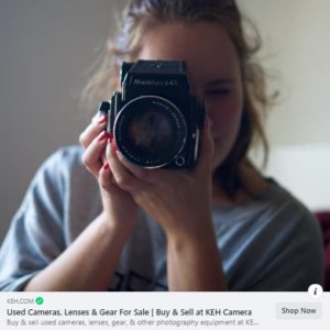 KEH.com ad. A photograph of a woman holding a camera to her eye. Text below the photograph advertises K E H. 