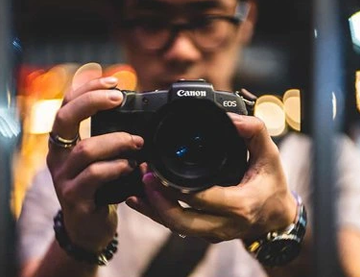 KEH-Case-Study-1 A photograph of a man holding a Canon camera in front of him.