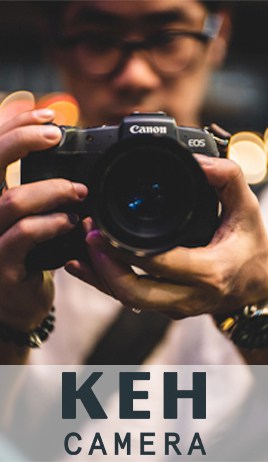 Logo: K E H Camera. A photograph of a man holding a camera.  