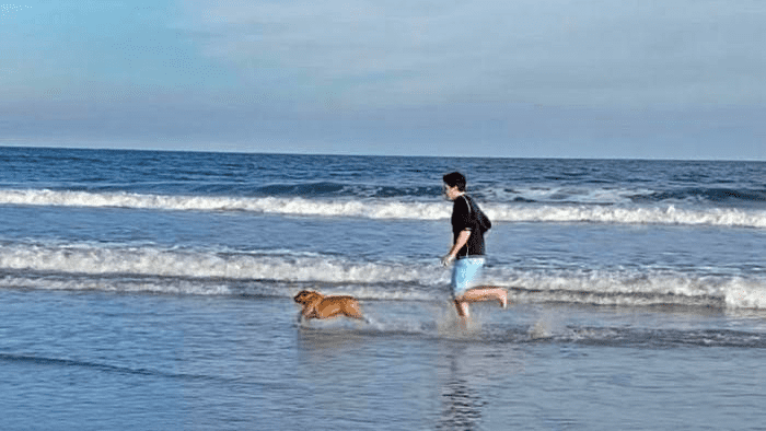 Michael Block and bulldog Logan running on the beach.