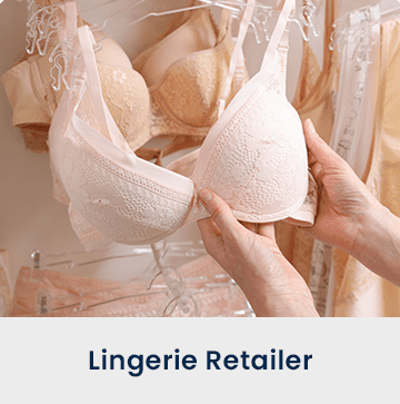 Hands holding a pink bra on a hanger. Caption: Lingerie Retailer.