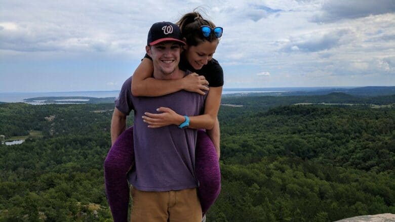 Paid Strategist Mike Ryan giving his spouse a piggyback ride at the top of a forest overlook.