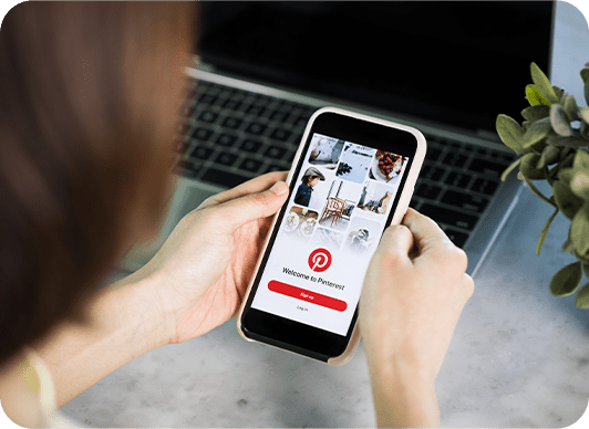 Person holding a mobile phone showing the login page for Pinterest.